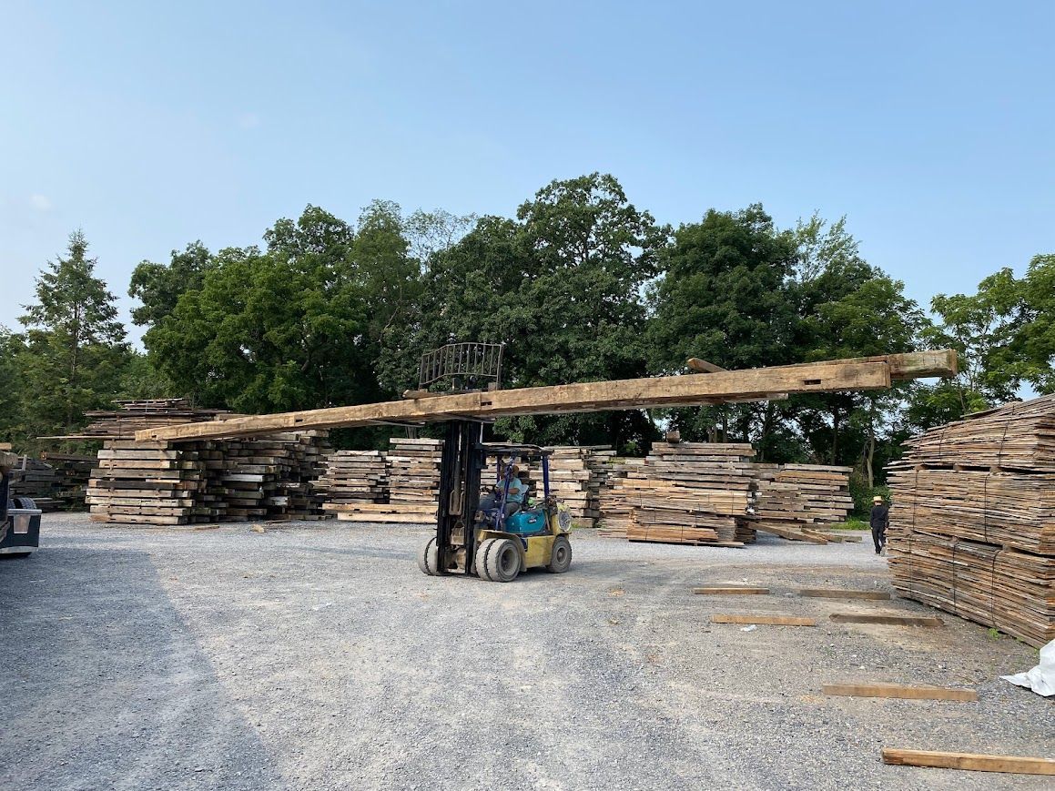Forklift moving timber at historic barn frame suppliers.