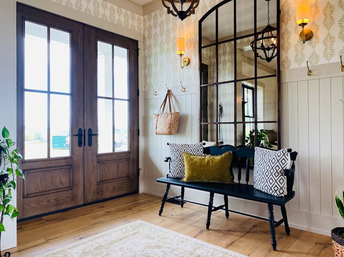 Modern farmhouse entryway with wooden doors, bench, and warm decor.
