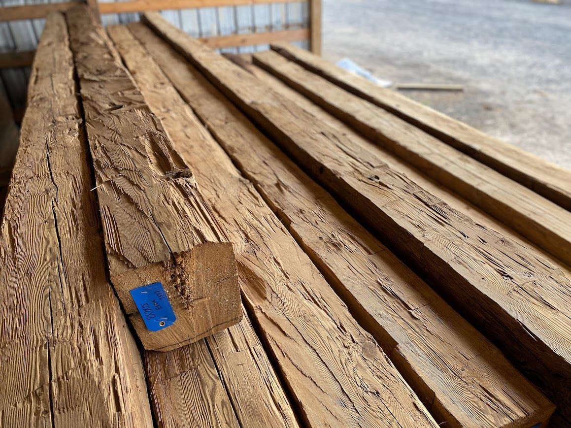 A stack of rough-sawn beams highlights timber recycling.