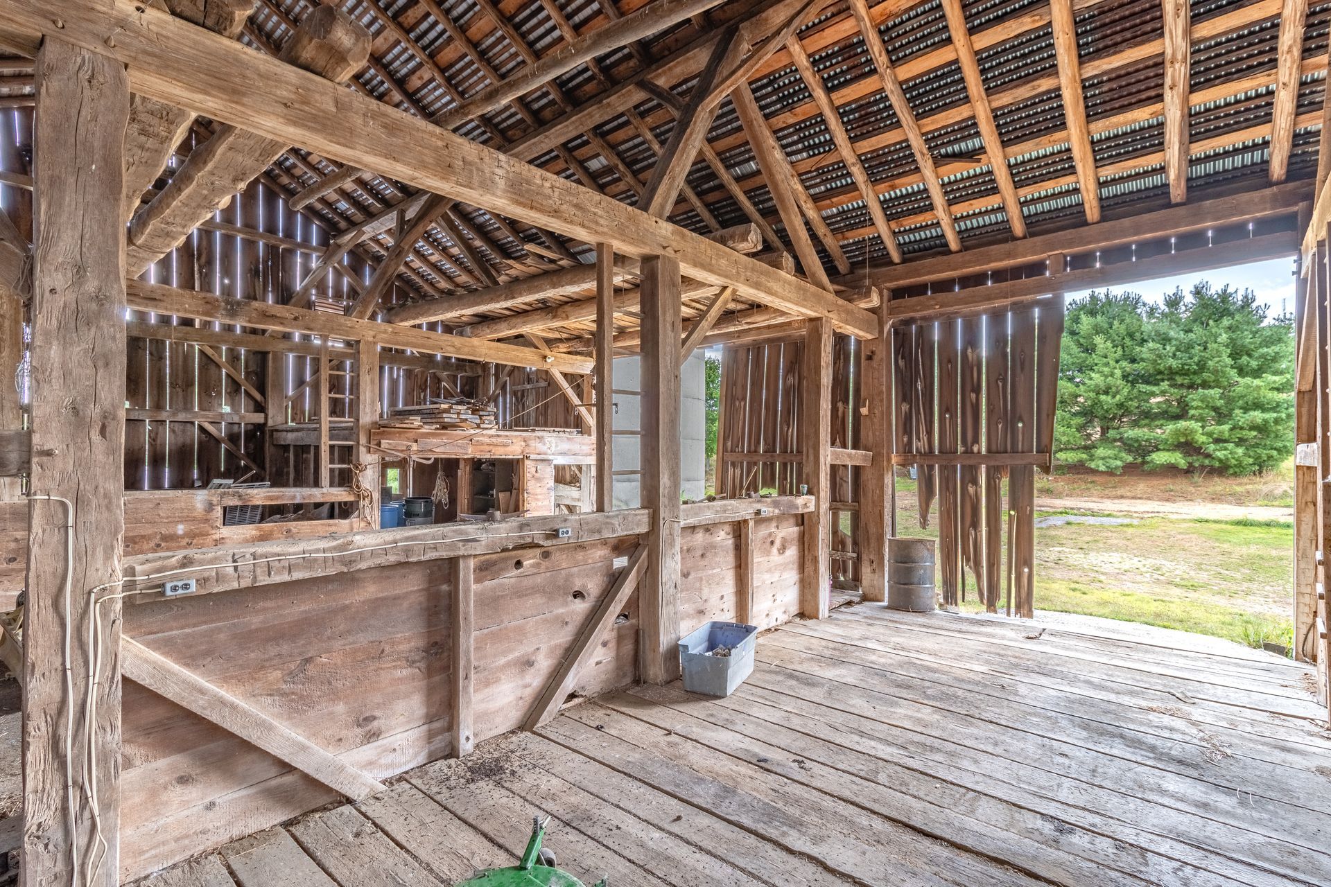 Interior of a rustic wooden barn undergoing historic barn restoration, with beams, planks, and natural light.
