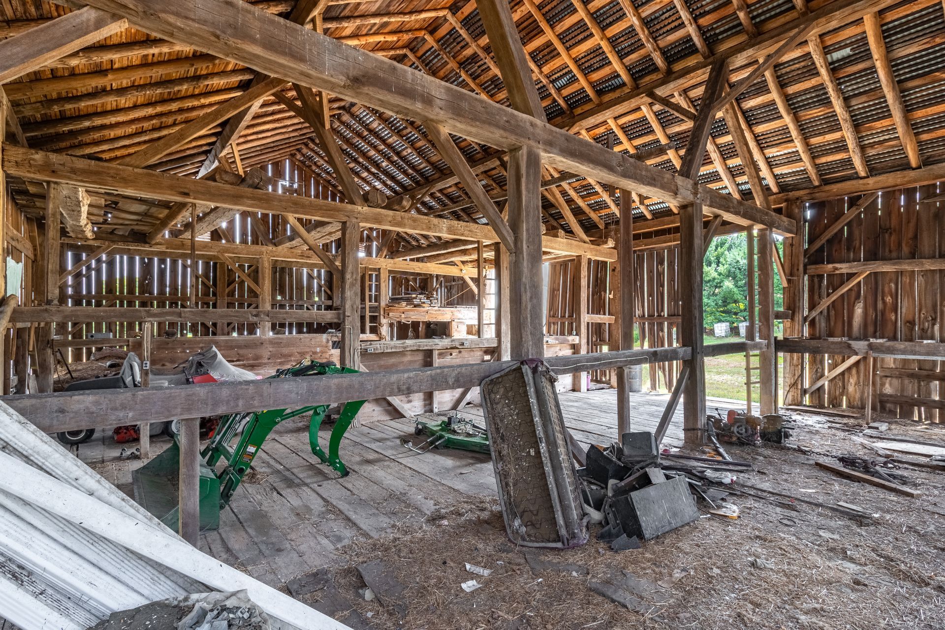 The inside of an old wooden barn with a green tractor in it.