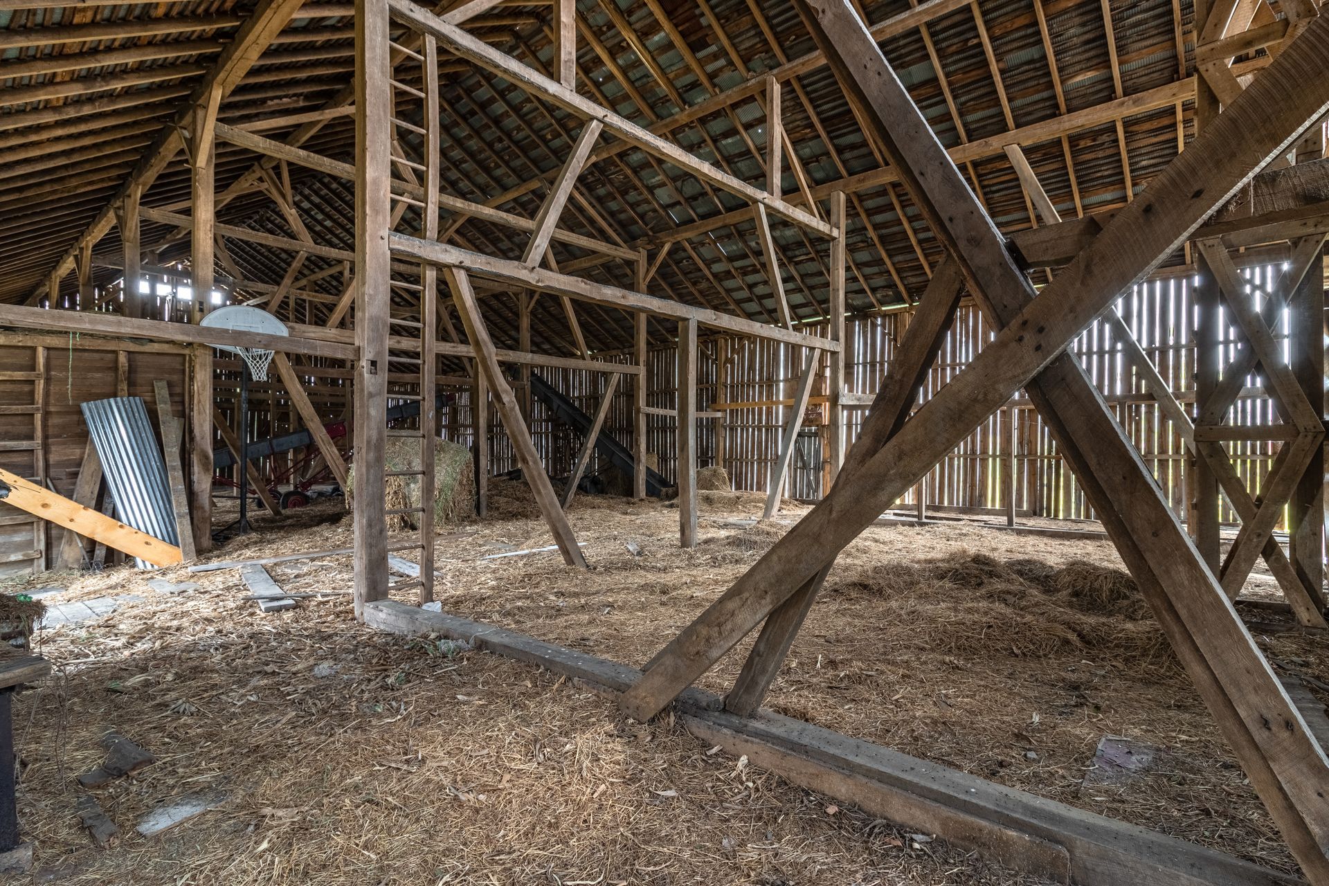 The inside of an old barn with wooden beams and a roof.