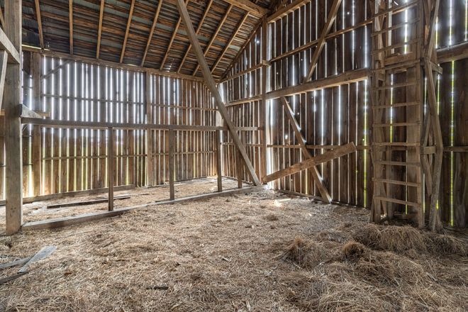 The inside of an old wooden barn filled with hay.