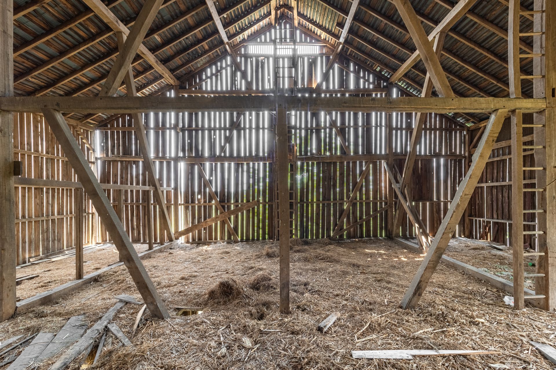 The inside of an old wooden barn with a wooden roof.