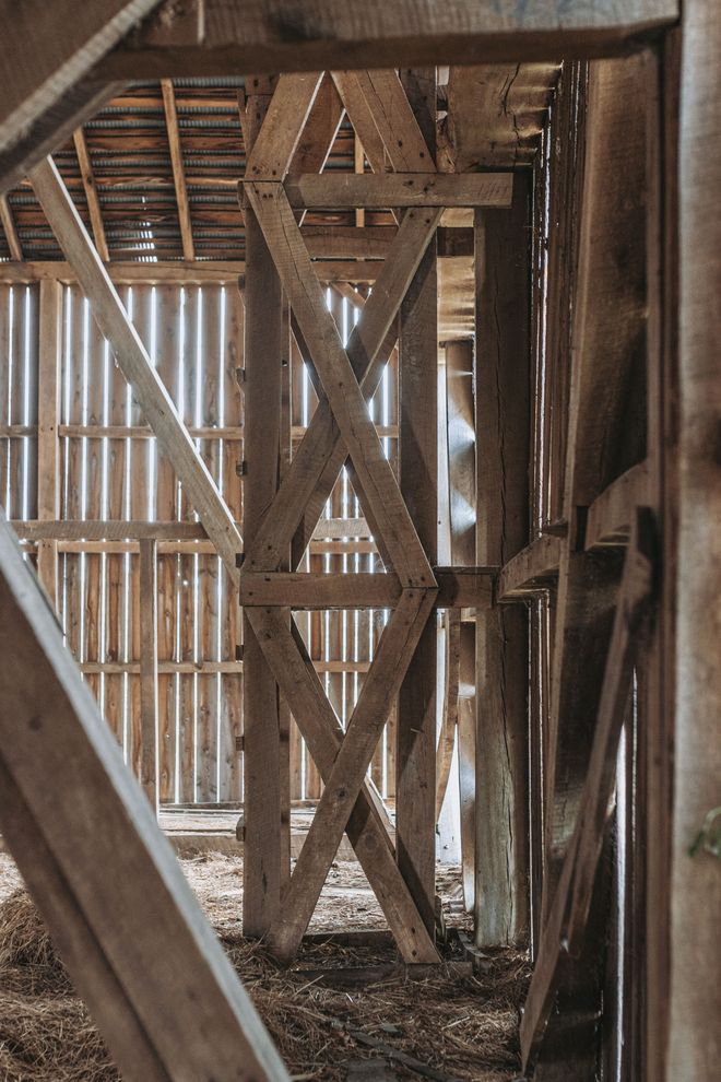 The inside of a barn with wooden beams and a metal roof.