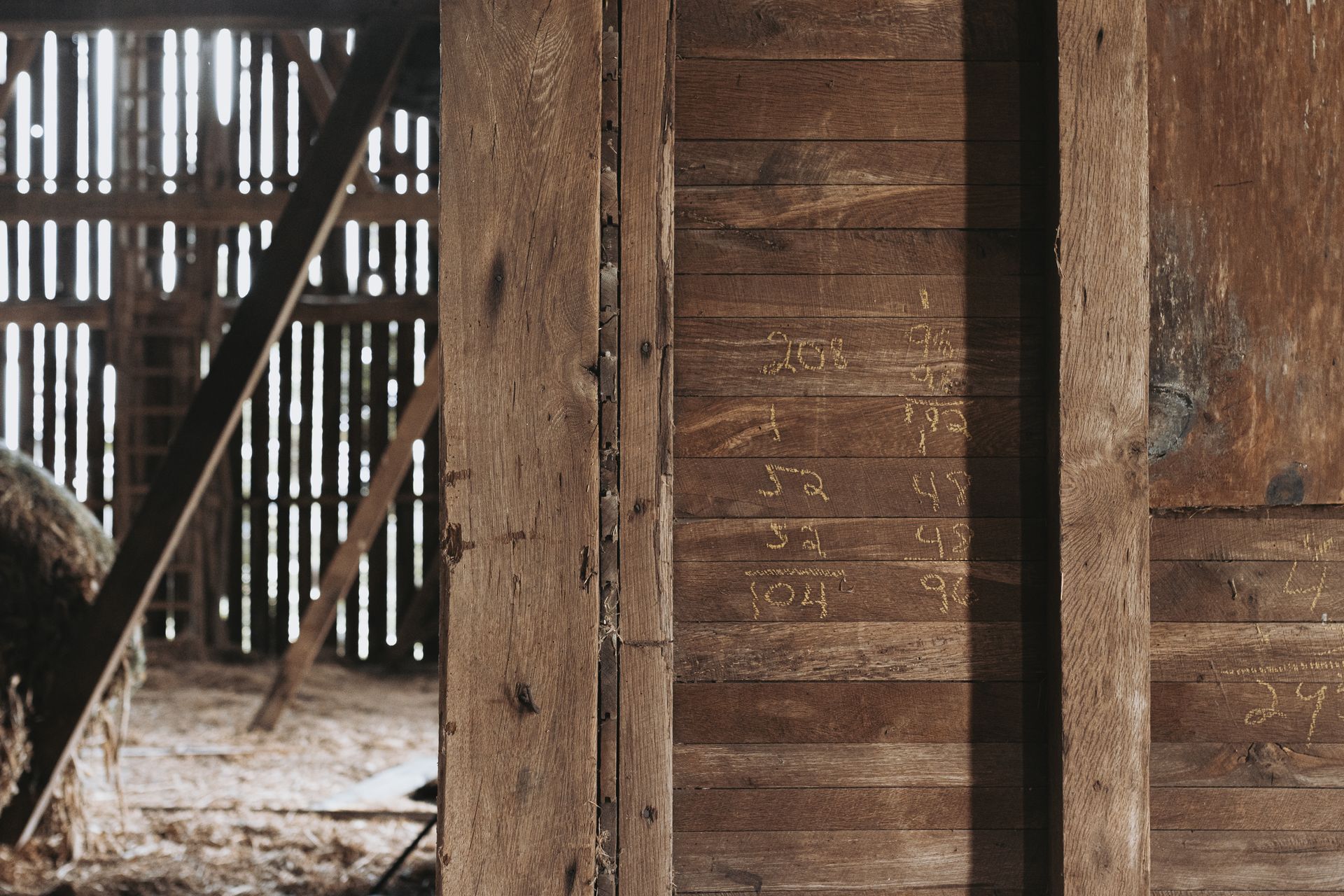 The inside of a wooden barn with a hay bale in the background.