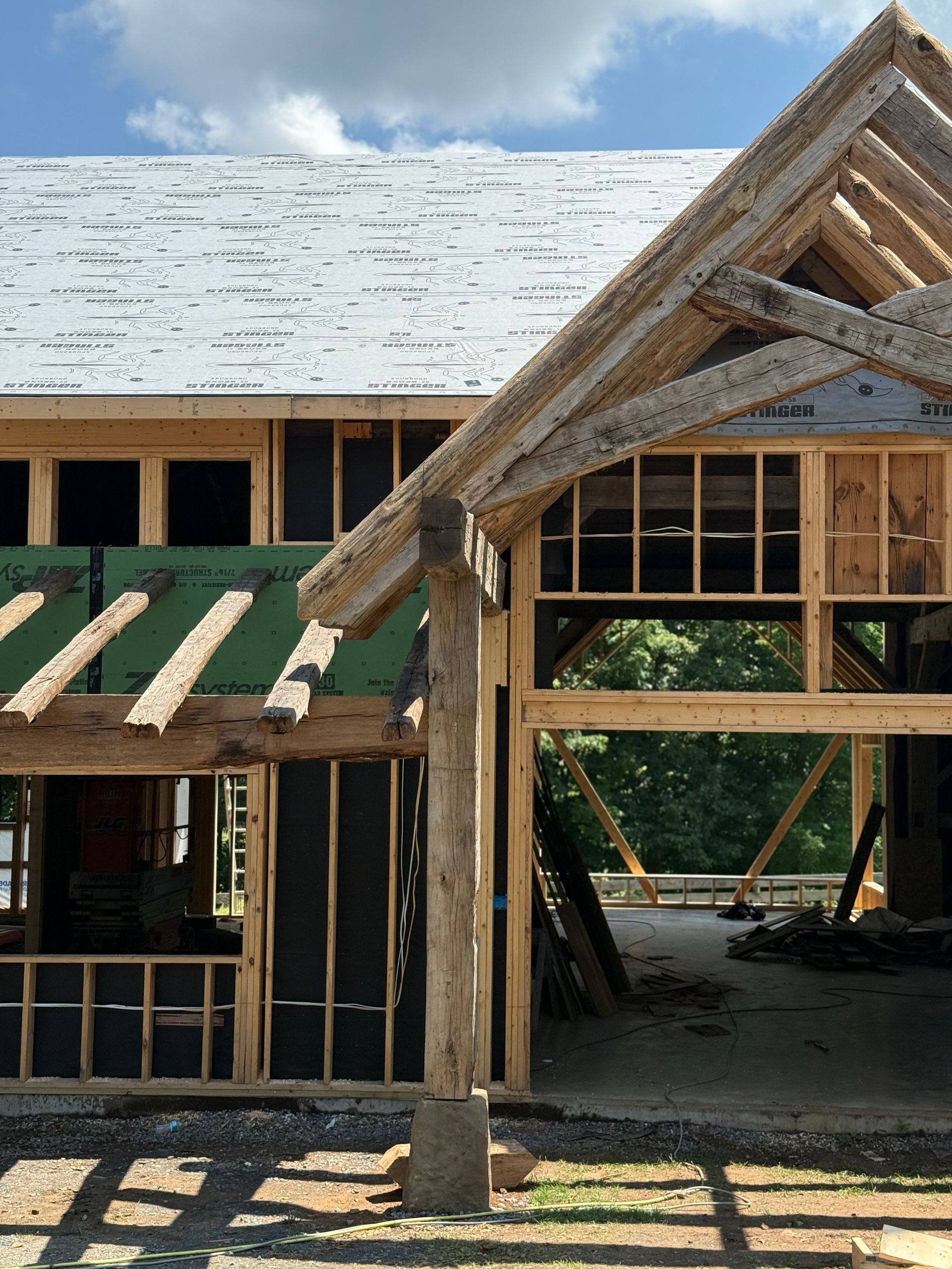 Sunny Pennsylvania construction site with wooden barn frame and green insulation visible.