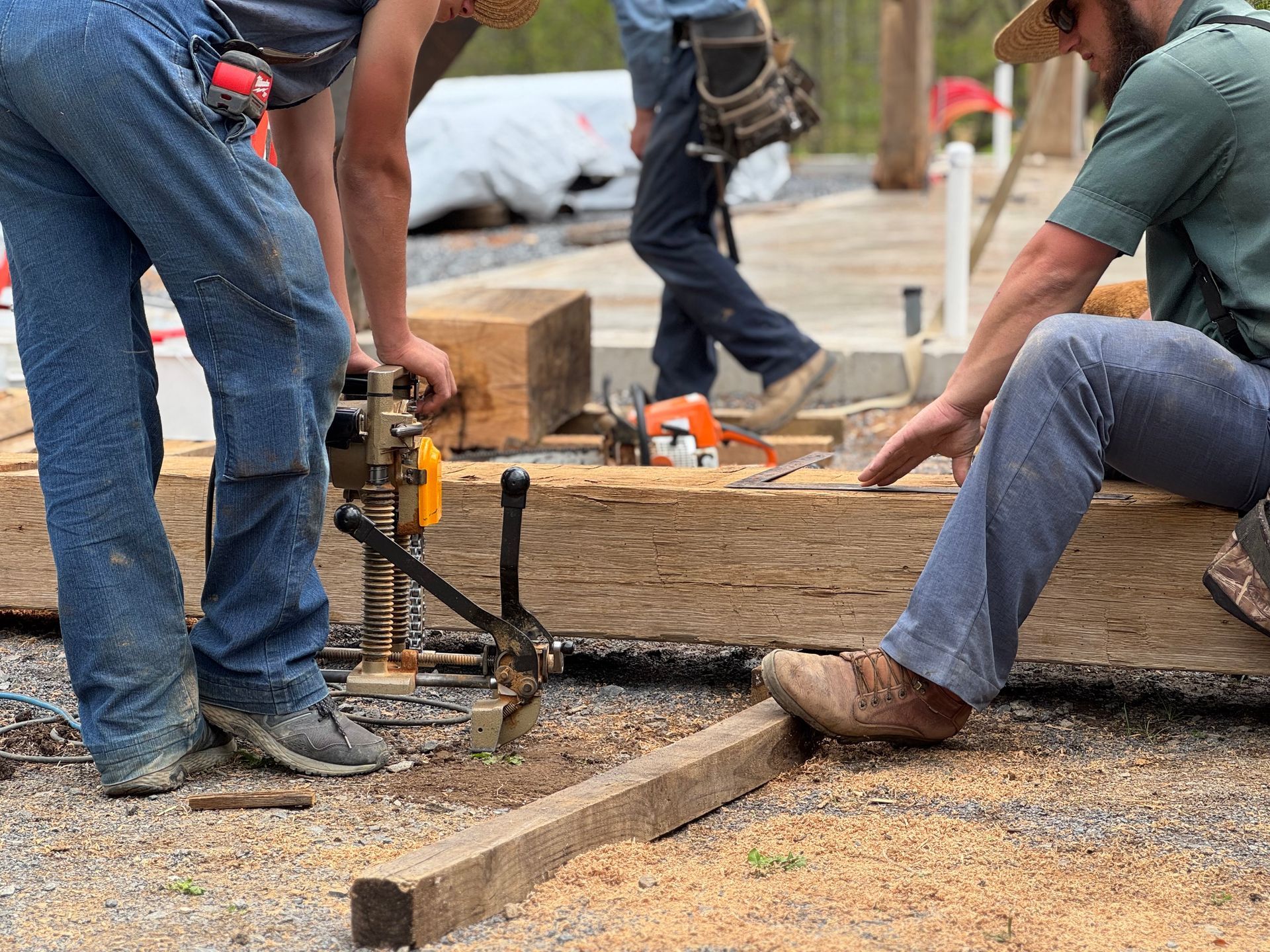 Workers crafting wooden beams with tools on a construction site, showcasing farmers building supply essentials for timber projects.