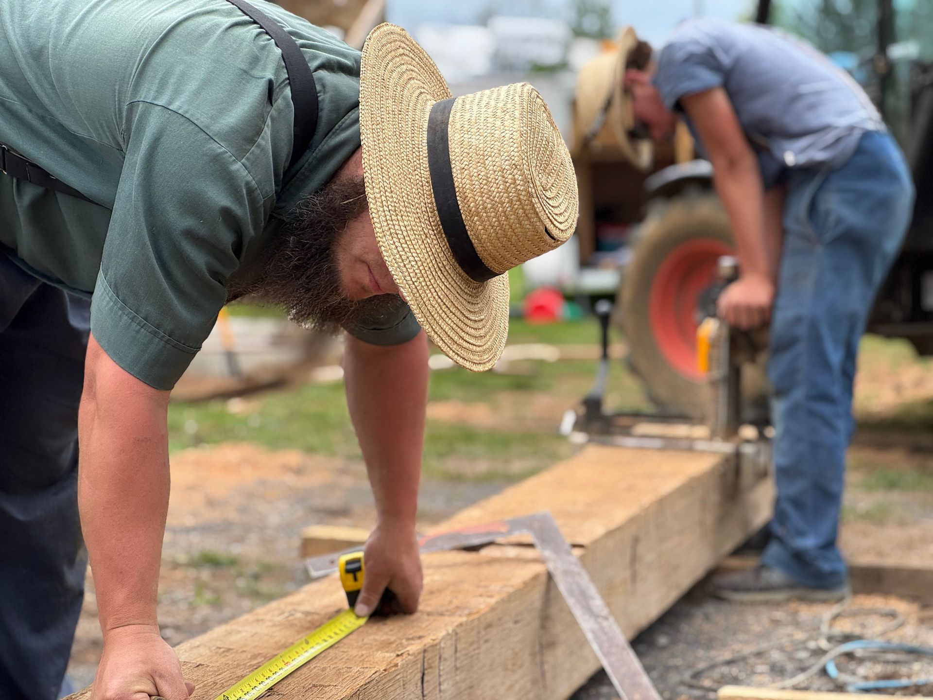 Two men measuring and working on a wooden beam as part of their craftsmanship and heritage restoration services.