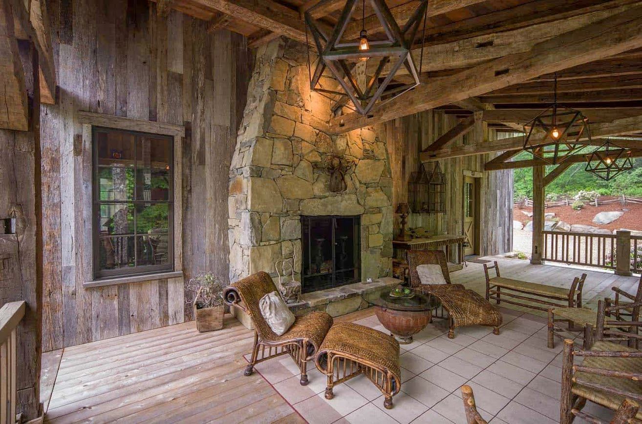 A barndominium with a stone fireplace and wicker furniture.