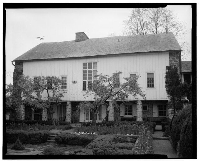 Historic American barn with wood and stone architecture, surrounded by a structured garden.