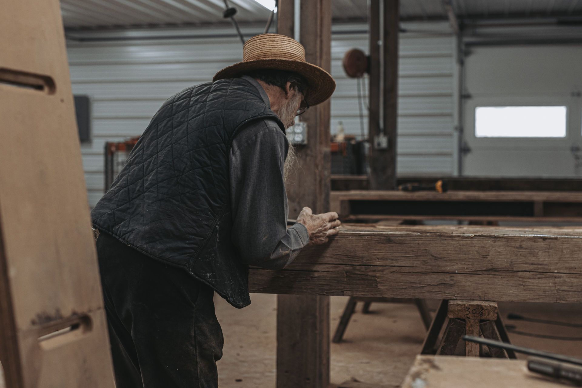 Craftsman working on reclaimed wood construction in a workshop.