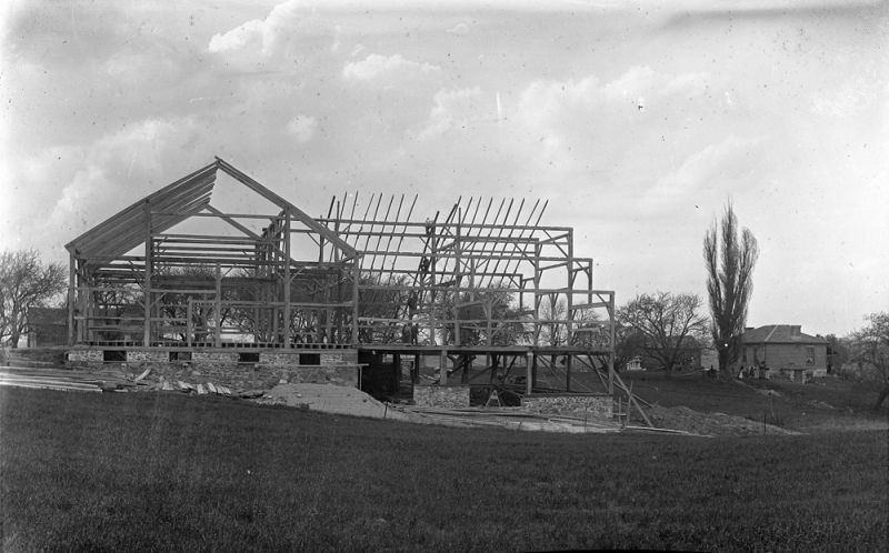 Wooden framework under construction in a field, showcasing historic barn frames.