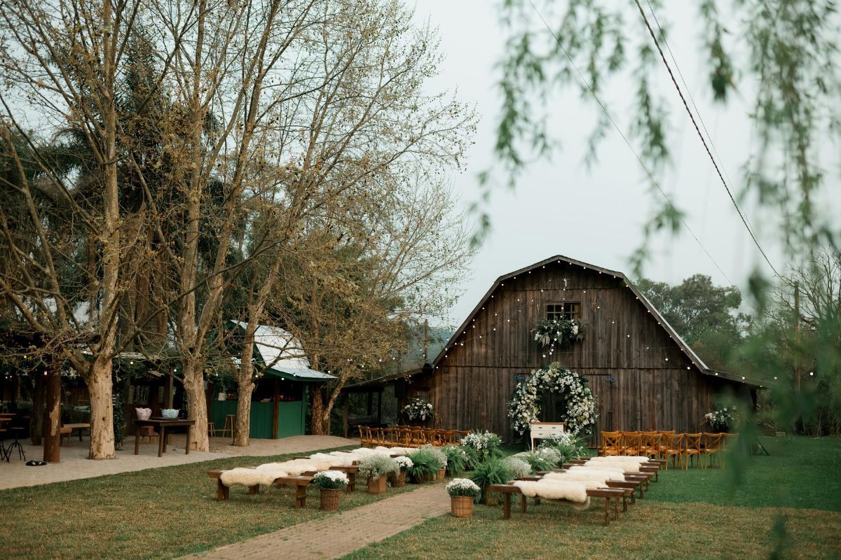 Outdoor barn ceremony setup with floral arch and benches, ideal for a wedding venue owner.