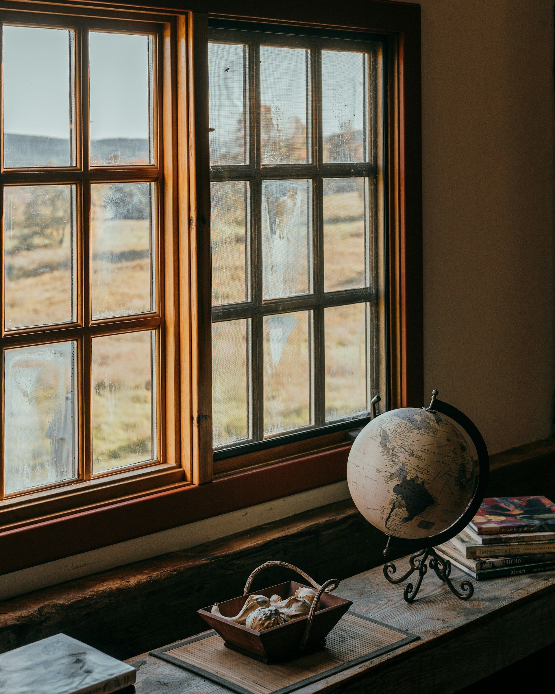 Ranch style house interior showing a rustic window view with globe, books, and autumn landscape.