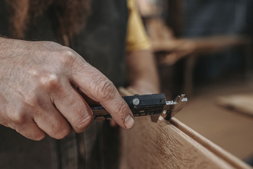 Hand measuring wood plank for precise rabbet joints.