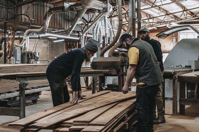 Workers processing wood for barn frame architectural planning.