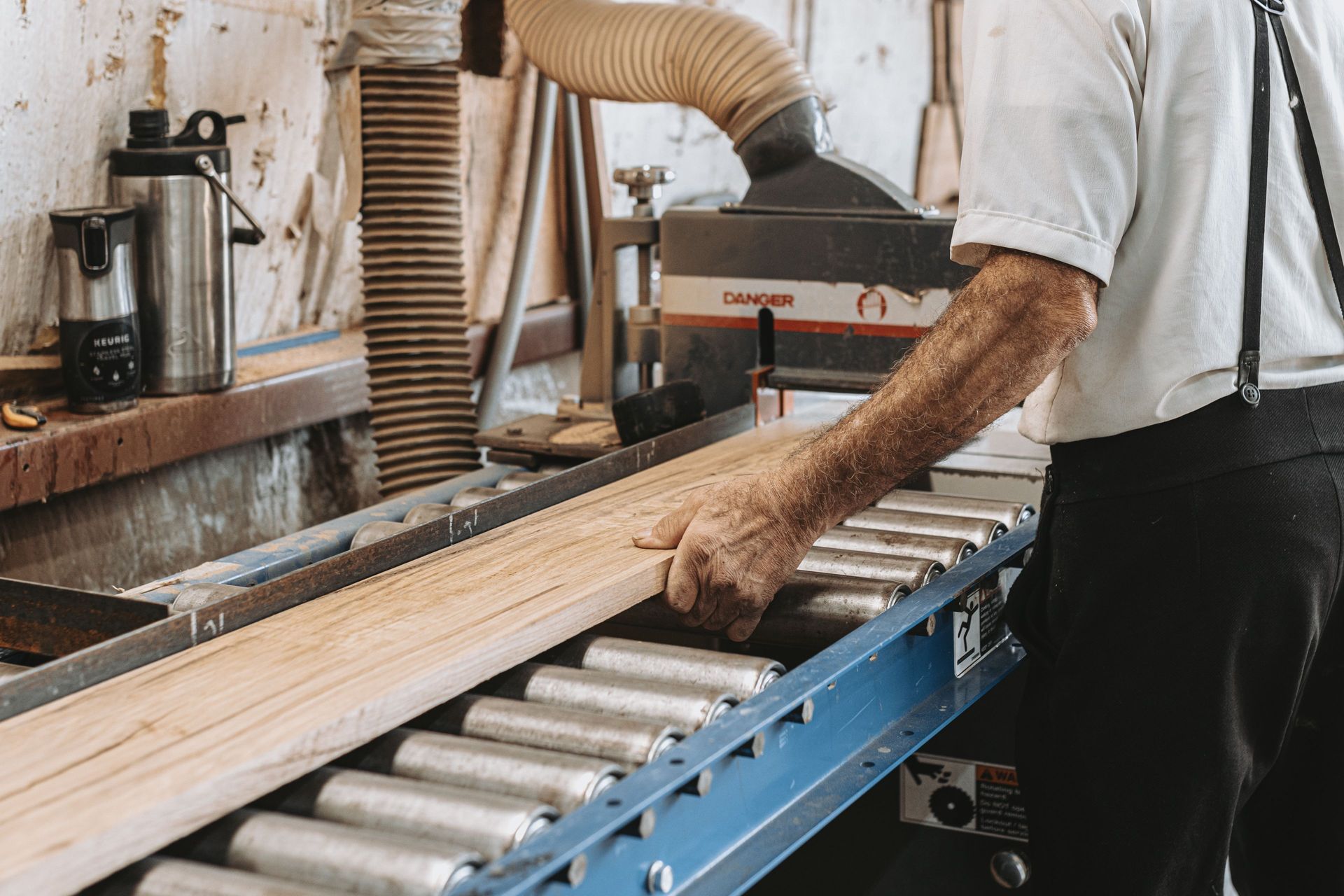 Worker guiding wood on a conveyor for barn frame reconstruction.
