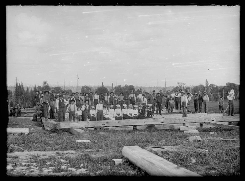 A black and white photo of a group of people standing in a field.