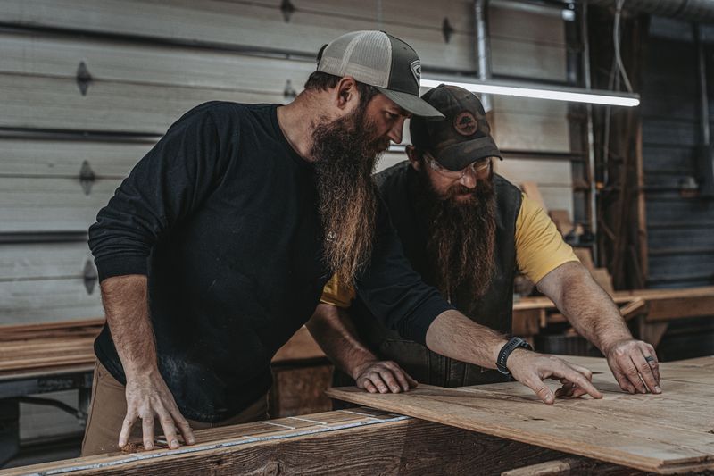 Two craftsmen collaborating on barn frame architectural planning.