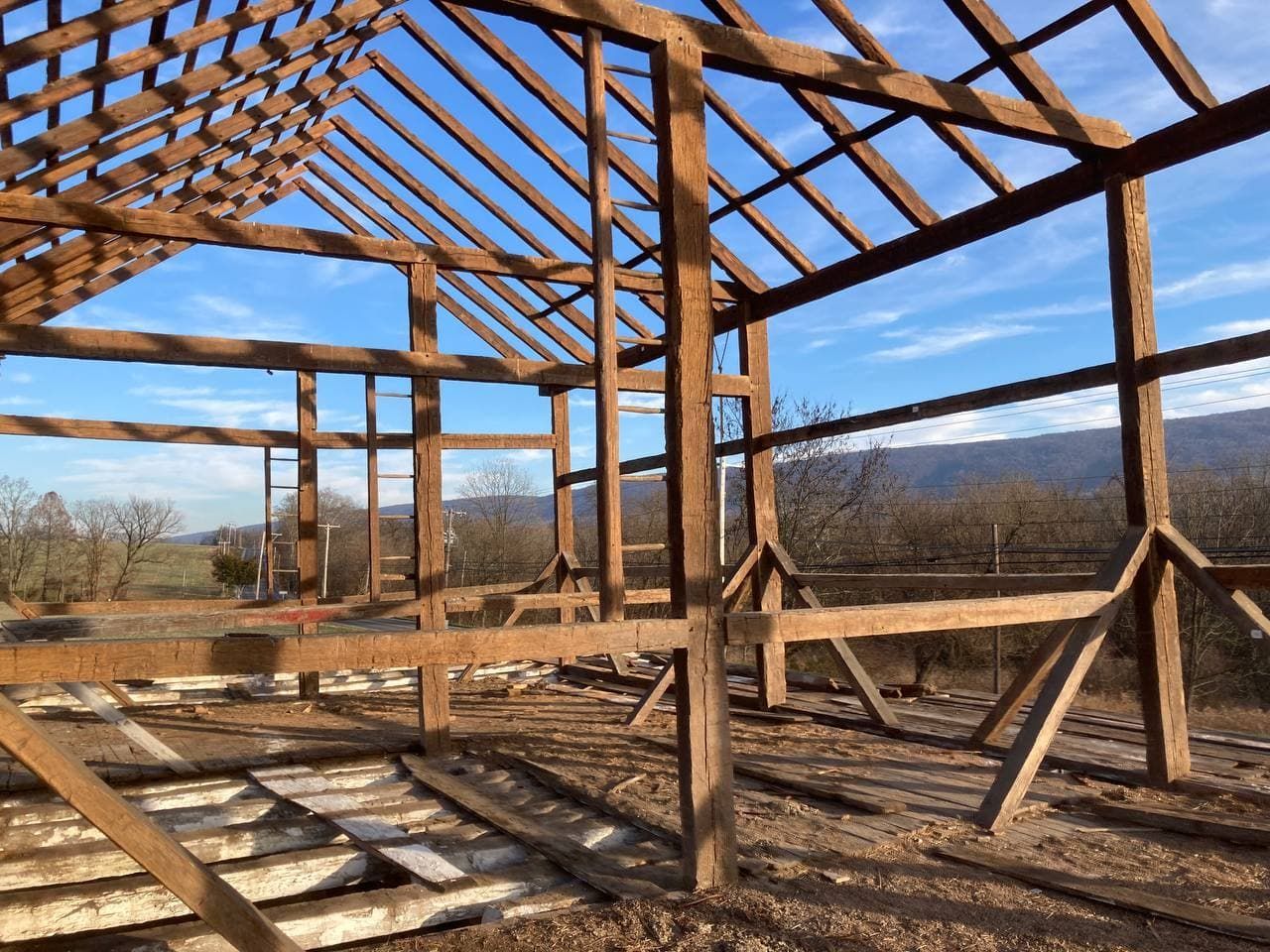 The inside of a barn under construction with a blue sky in the background.