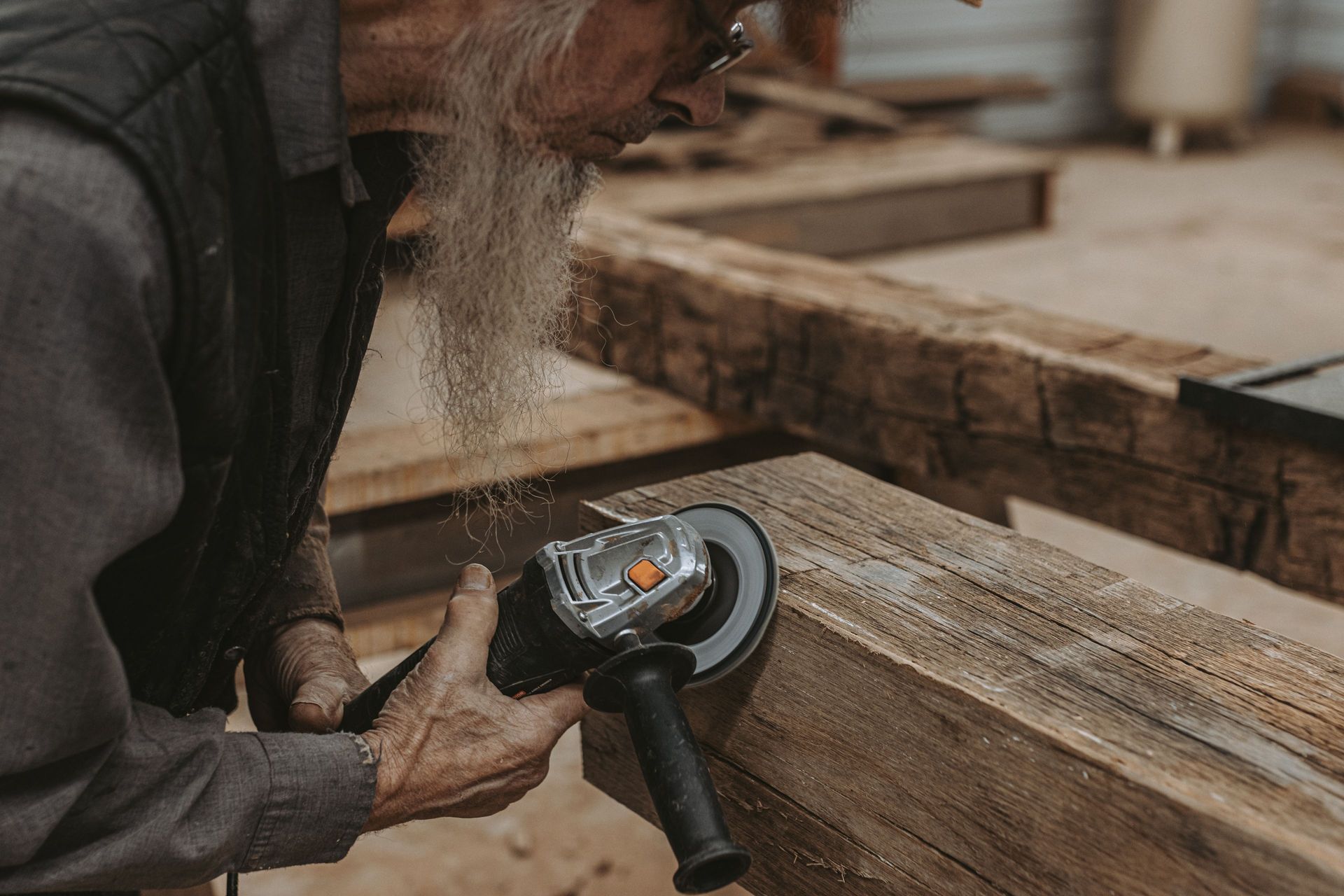 Worker using angle grinder for timber frame restoration.