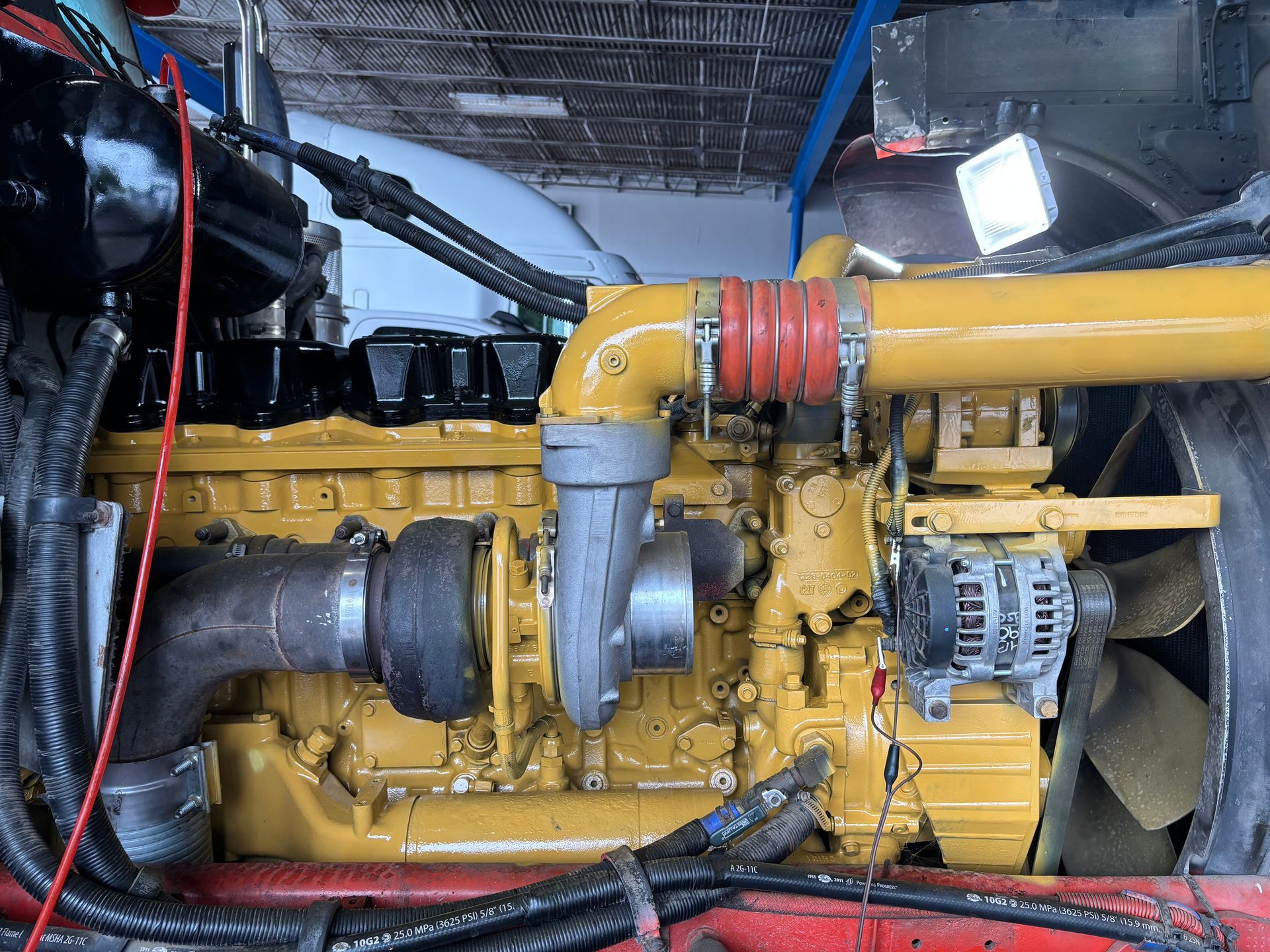A heavy-duty yellow industrial engine with a turbocharger and metallic components housed within a workshop setting.
