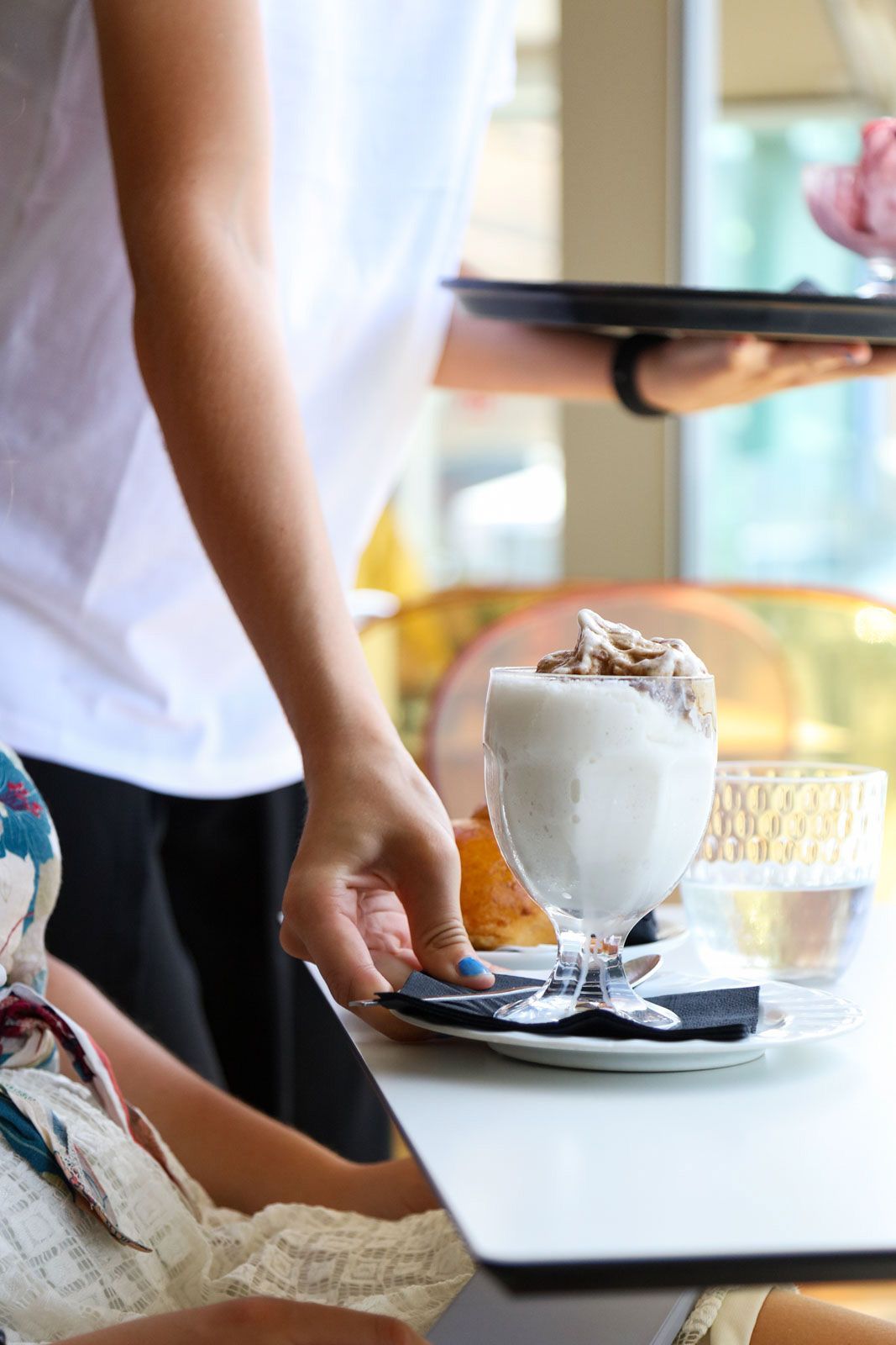 Un cameriere che mette un milkshake sul tavolo di un bar.