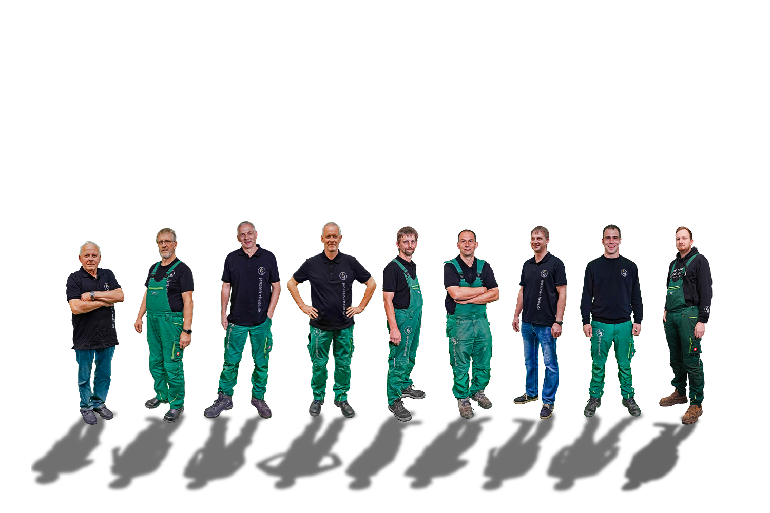 Neun Personen stehen in einer Reihe vor einem weißen Hintergrund und tragen Arbeitskleidung, meist grüne Overalls oder schwarze Hemden.