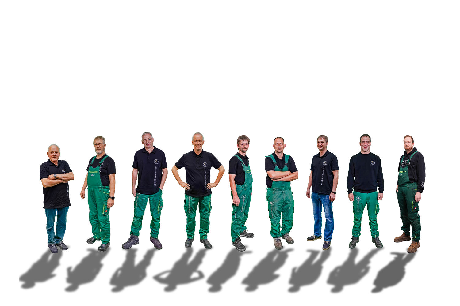 Neun Personen stehen in einer Reihe vor einem weißen Hintergrund und tragen Arbeitskleidung, meist grüne Overalls oder schwarze Hemden.