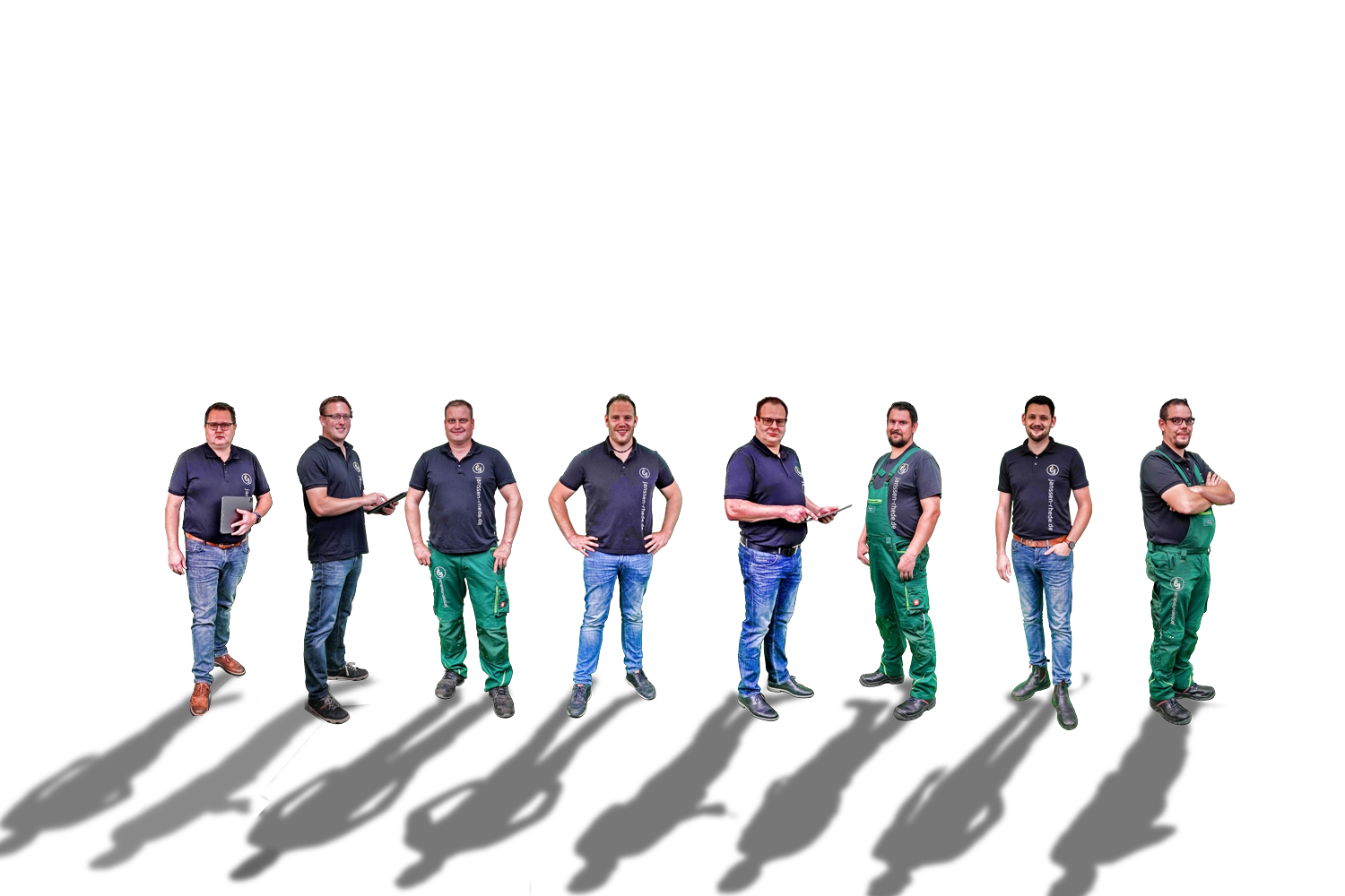 Acht Personen in Arbeitskleidung, einige in Poloshirts und Jeans, andere in grünen Overalls, stehen in einer Reihe.