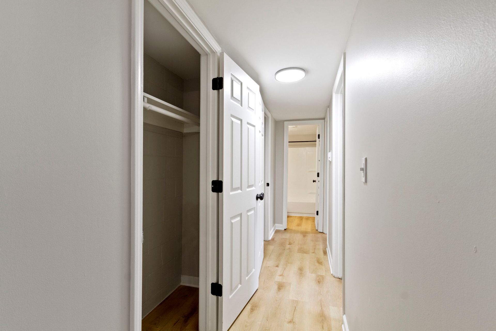 Narrow hallway with white walls, a closet, and open white doors.