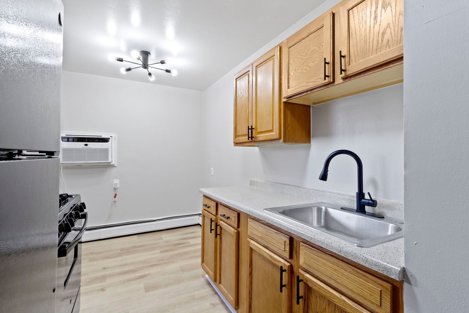 A kitchen with light wood cabinets, a stainless steel sink, and a refrigerator.