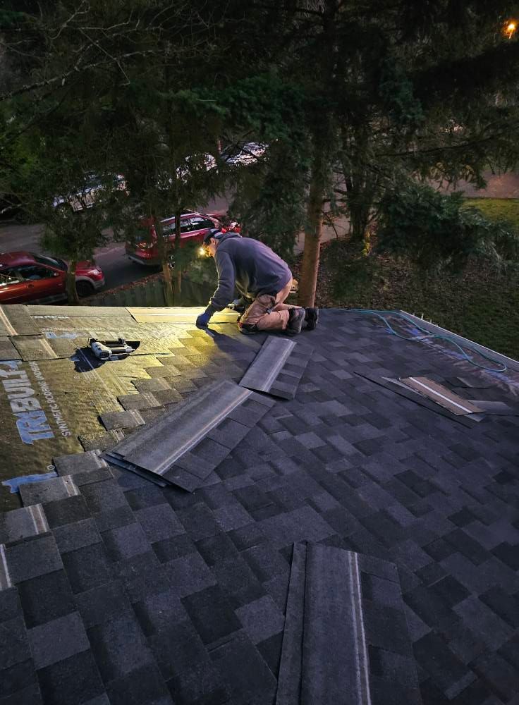 A man is working on a roof at night.