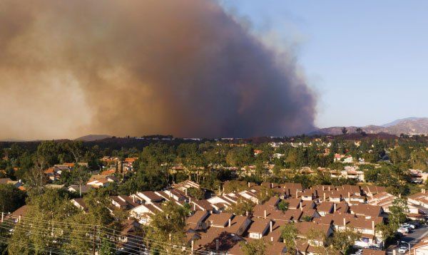 An aerial view of a residential area with a large cloud of smoke coming out of it.