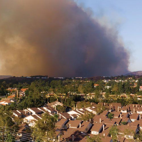 An aerial view of a residential area with smoke coming out of the sky