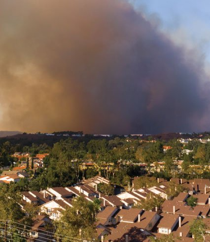 An aerial view of a residential area with smoke coming out of the sky