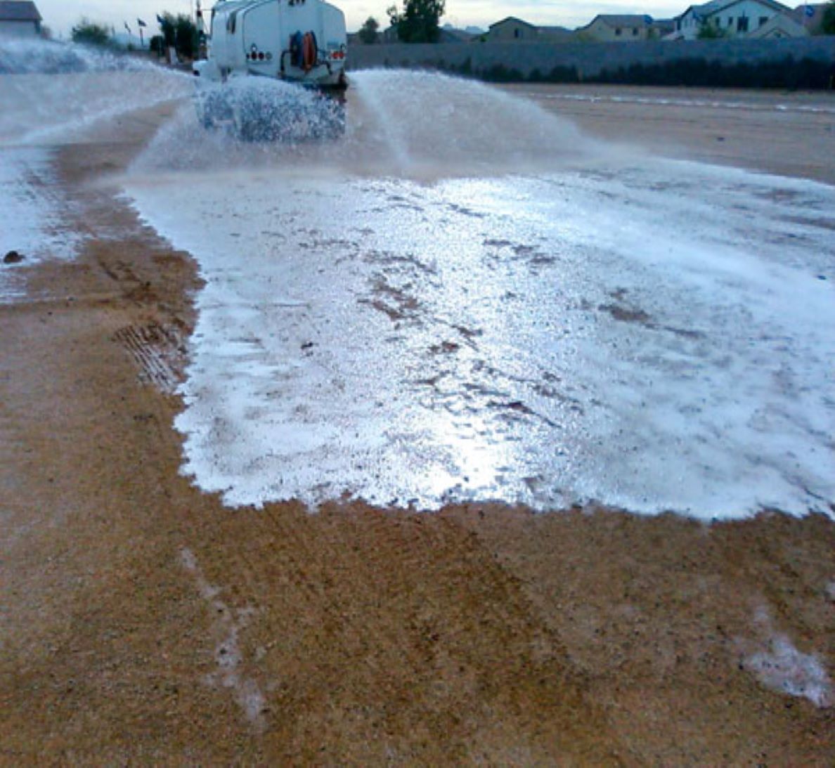 A truck is spraying water on a dirt road.