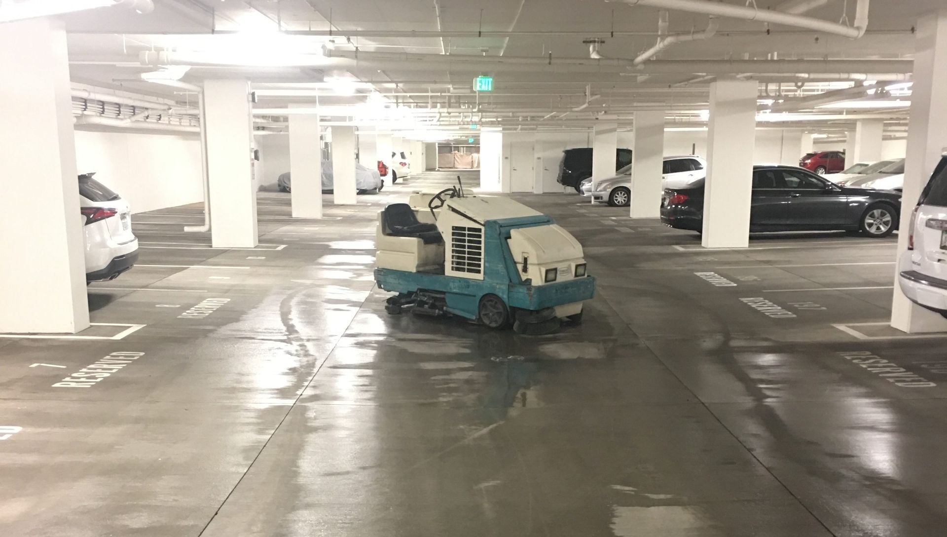 A machine is cleaning the floor of a parking garage.