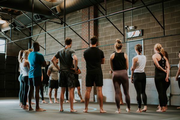 People in athletic wear standing in a circle inside a gym, looking forward.