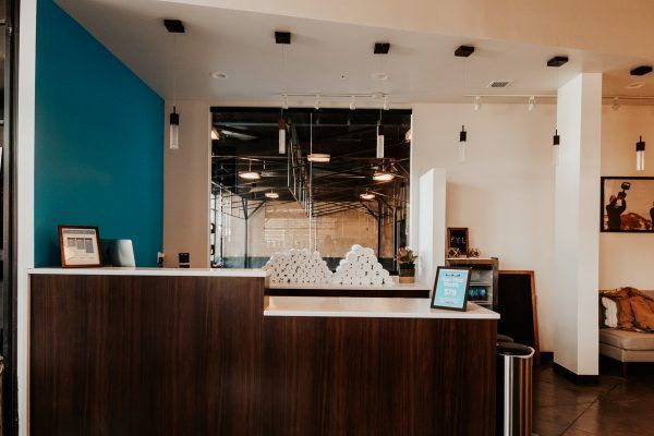 Reception desk in modern office with teal wall and dark wood paneling.