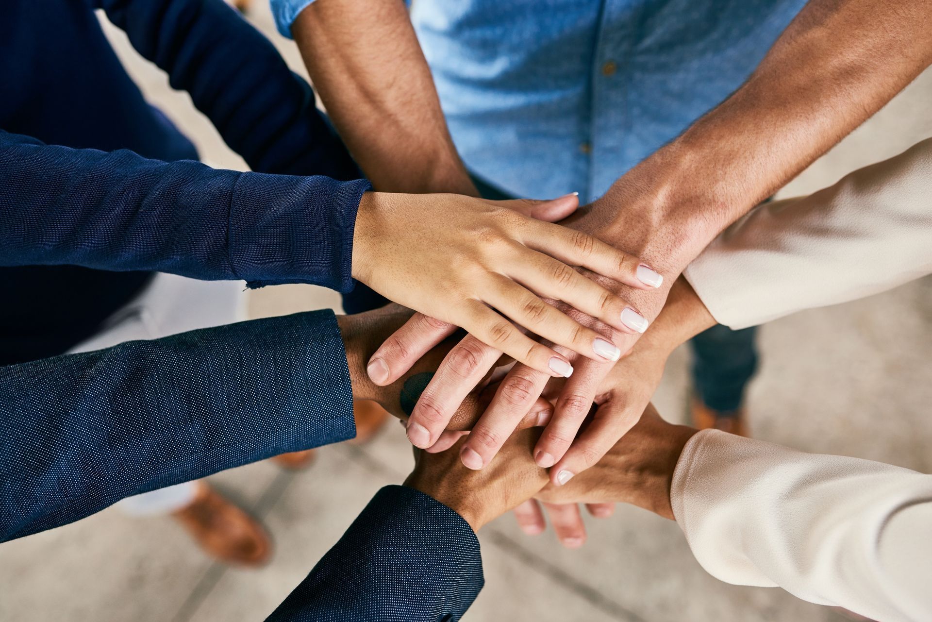 Hands stacked together in a team huddle, representing unity and collaboration.