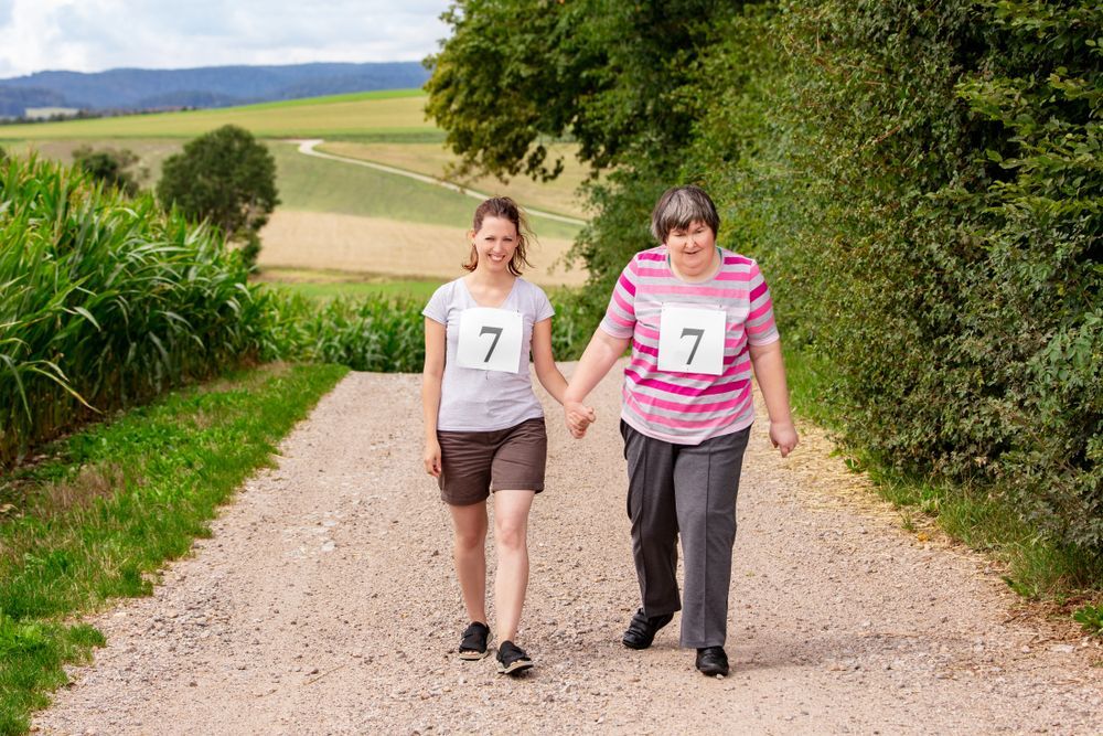 Two Women Walking Down A Dirt Road Holding Hands — Comfort N Care Support QLD Pty Ltd In Toowoomba City, QLD