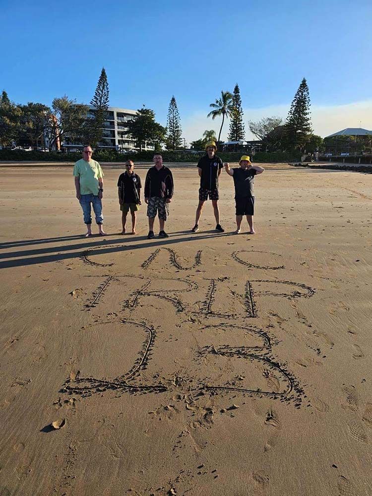 A Group of People Standing on A Beach with A Star Drawn in The Sand — Comfort N Care Support QLD Pty Ltd In Toowoomba City, QLD