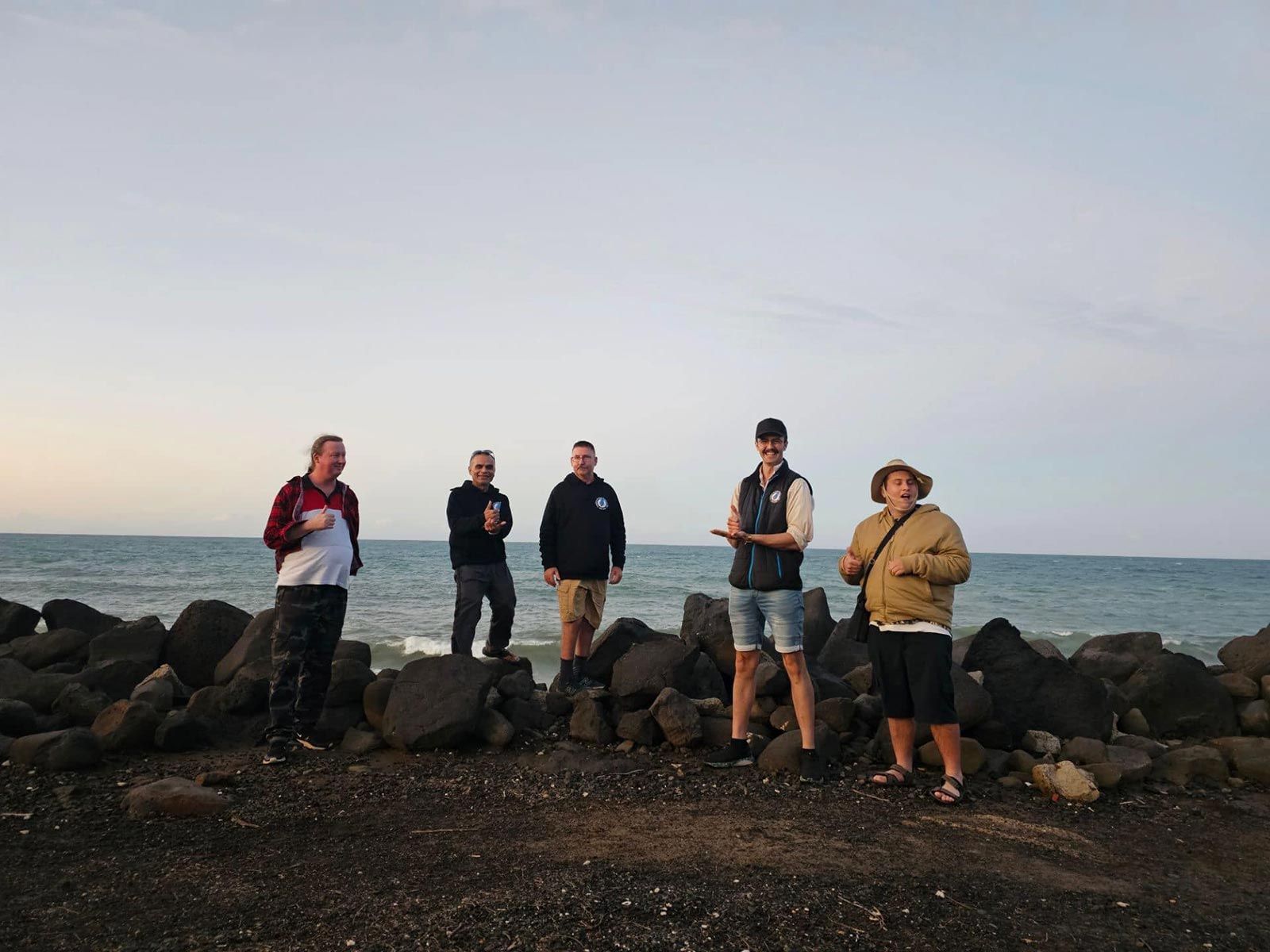 A Group of People Are Standing on A Rocky Beach Near the Ocean — Comfort N Care Support QLD Pty Ltd In Toowoomba City, QLD