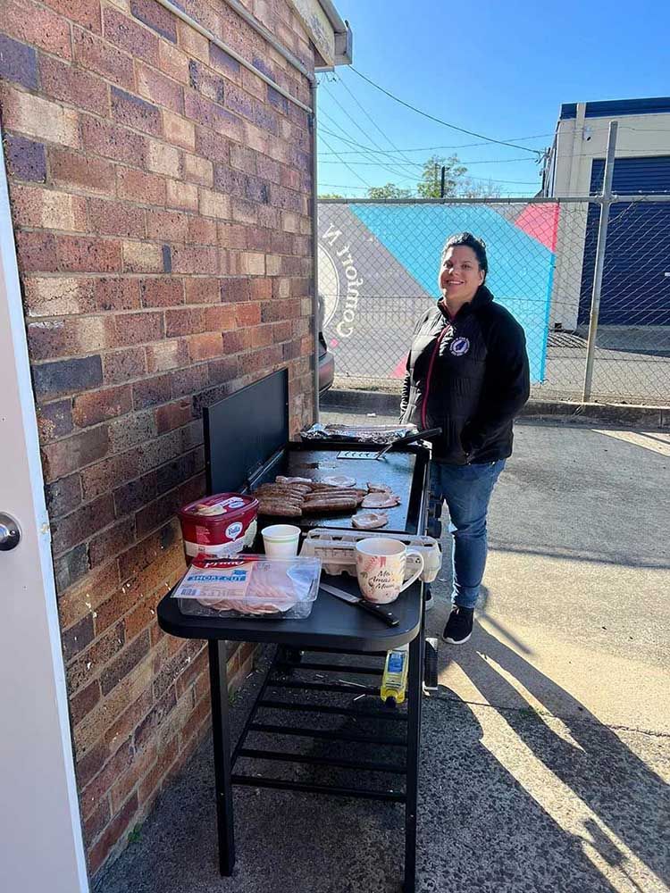 A Woman Is Standing in Front of A Table with Food on It — Comfort N Care Support QLD Pty Ltd In Toowoomba City, QLD