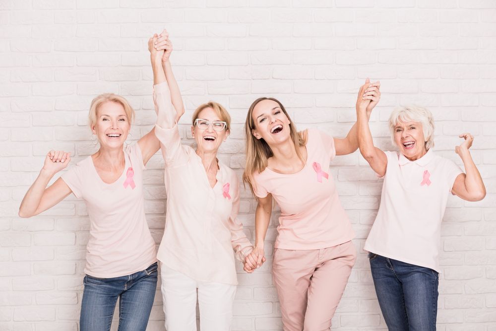 Group Of Women Wearing Pink Breast Cancer Awareness Shirts Are Holding Hands — Comfort N Care Support QLD Pty Ltd In Goondiwindi, QLD