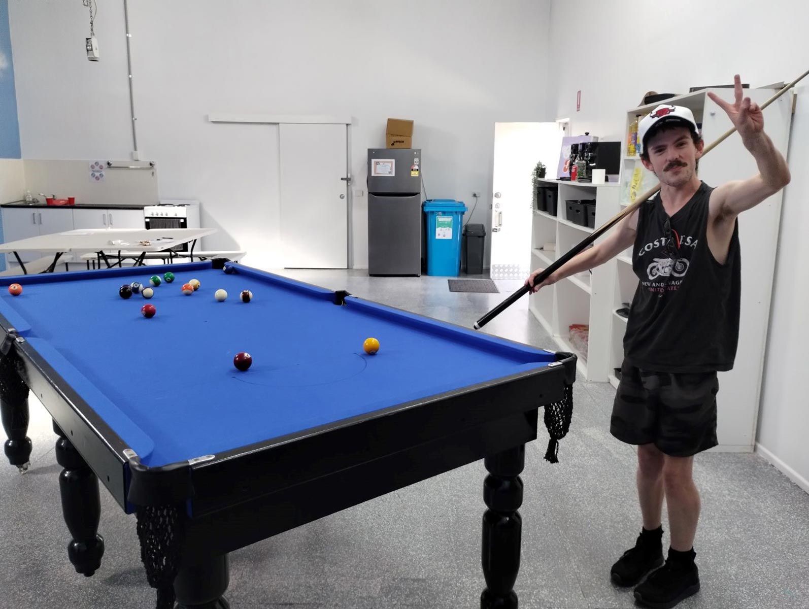 A Man Is Holding a Pool Cue in Front of A Pool Table — Comfort N Care Support QLD Pty Ltd In Highfields, QLD