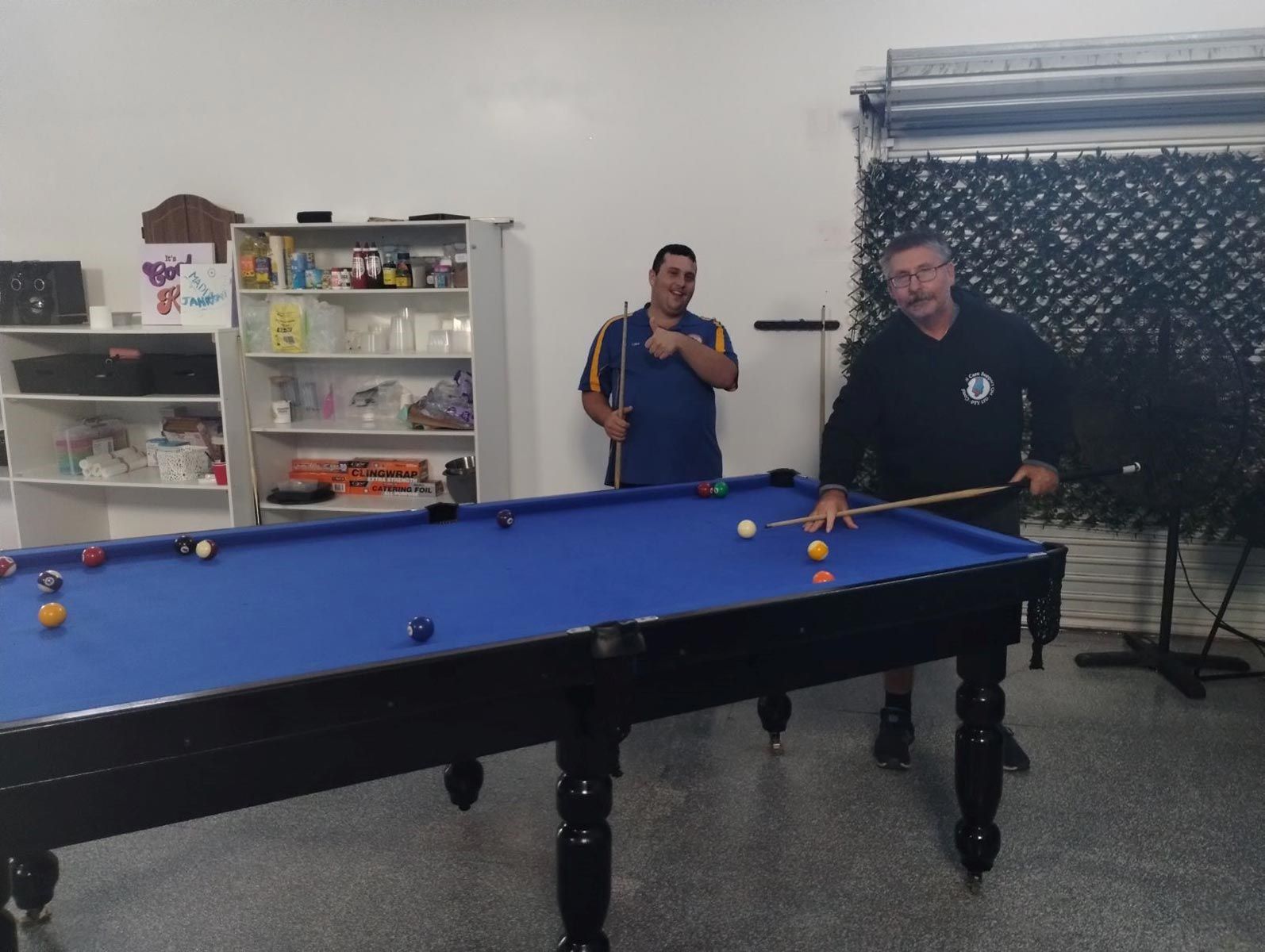 Two Men Are Playing Pool in A Room with A Pool Table — Comfort N Care Support QLD Pty Ltd In Highfields, QLD