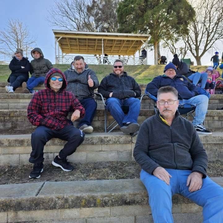 Group of People Wearing Jackets, Sitting on Stairs and Smiling on a Cold Day - Comfort N Care Support QLD PTY LTD